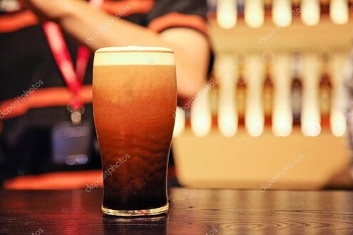Barman che spilla una pinta di Guinness al bancone di un pub